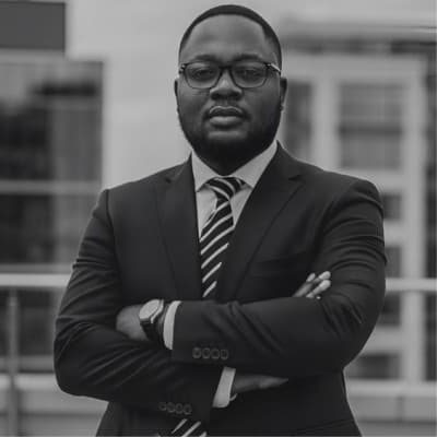 Godfred Ofosu Asante wearing a suit, with his arms folded